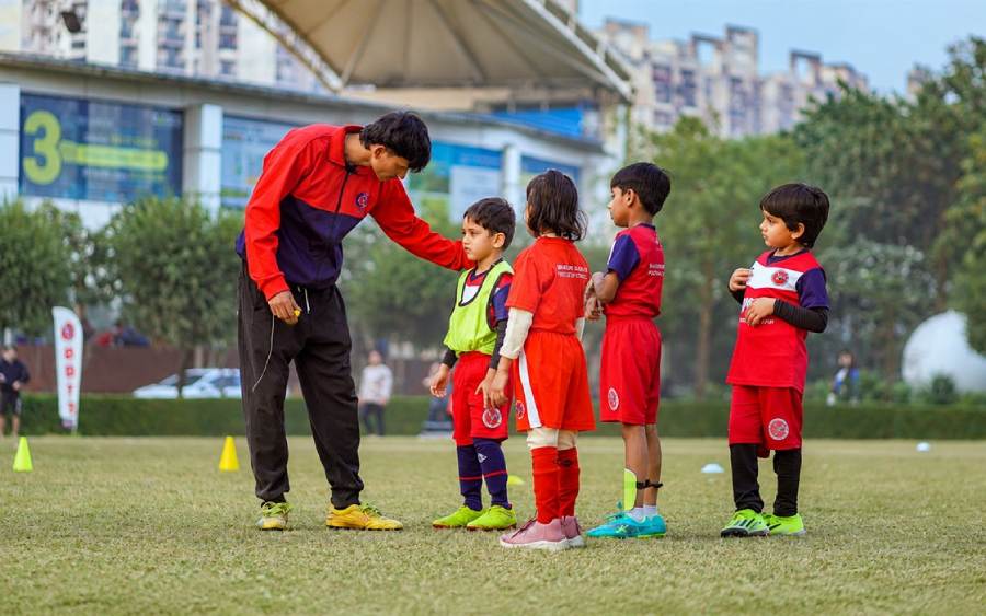A BBFS coach guiding young players through an age-specific football session